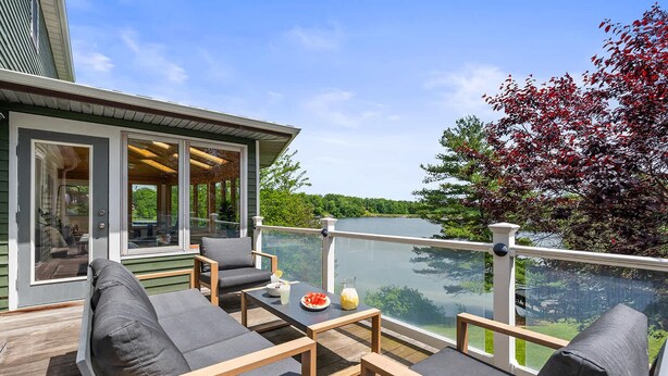 Une terrasse avec des sièges, une table avec des boissons et une vue sur un lac.