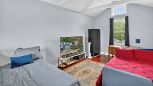 A bedroom with a bed, a TV, a desk, and a window. - Charming Uptown Guest Suite Private Bed & Bath (New Orleans)