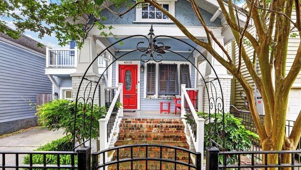 A two-story house with a red door, a brick staircase, and a white railing. - Charming Uptown Guest Suite Private Bed & Bath (New Orleans)