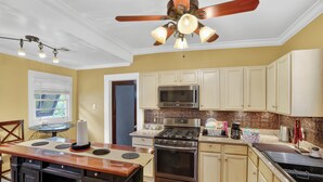 A kitchen with a central island, a ceiling fan, and a microwave. - Charming Uptown Guest Suite Private Bed & Bath (New Orleans)