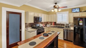 A kitchen with a central island, stainless steel appliances, and a ceiling fan. - Charming Uptown Guest Suite Private Bed & Bath (New Orleans)