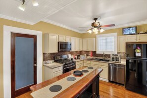 Una cocina con una isla central, electrodomésticos de acero inoxidable y un ventilador de techo.
