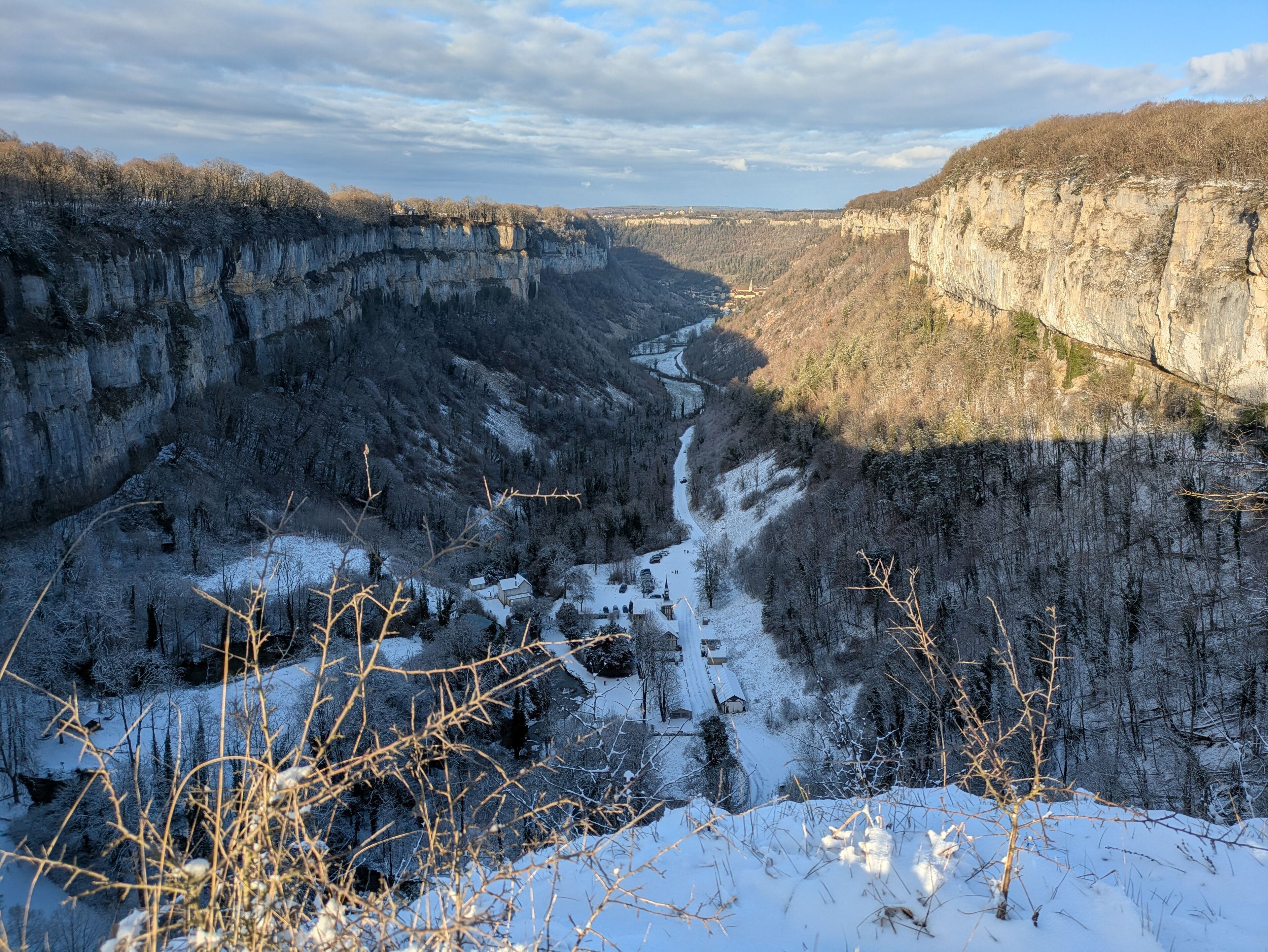 Un paysage hivernal avec une rivière, des falaises et une végétation clairsemée.