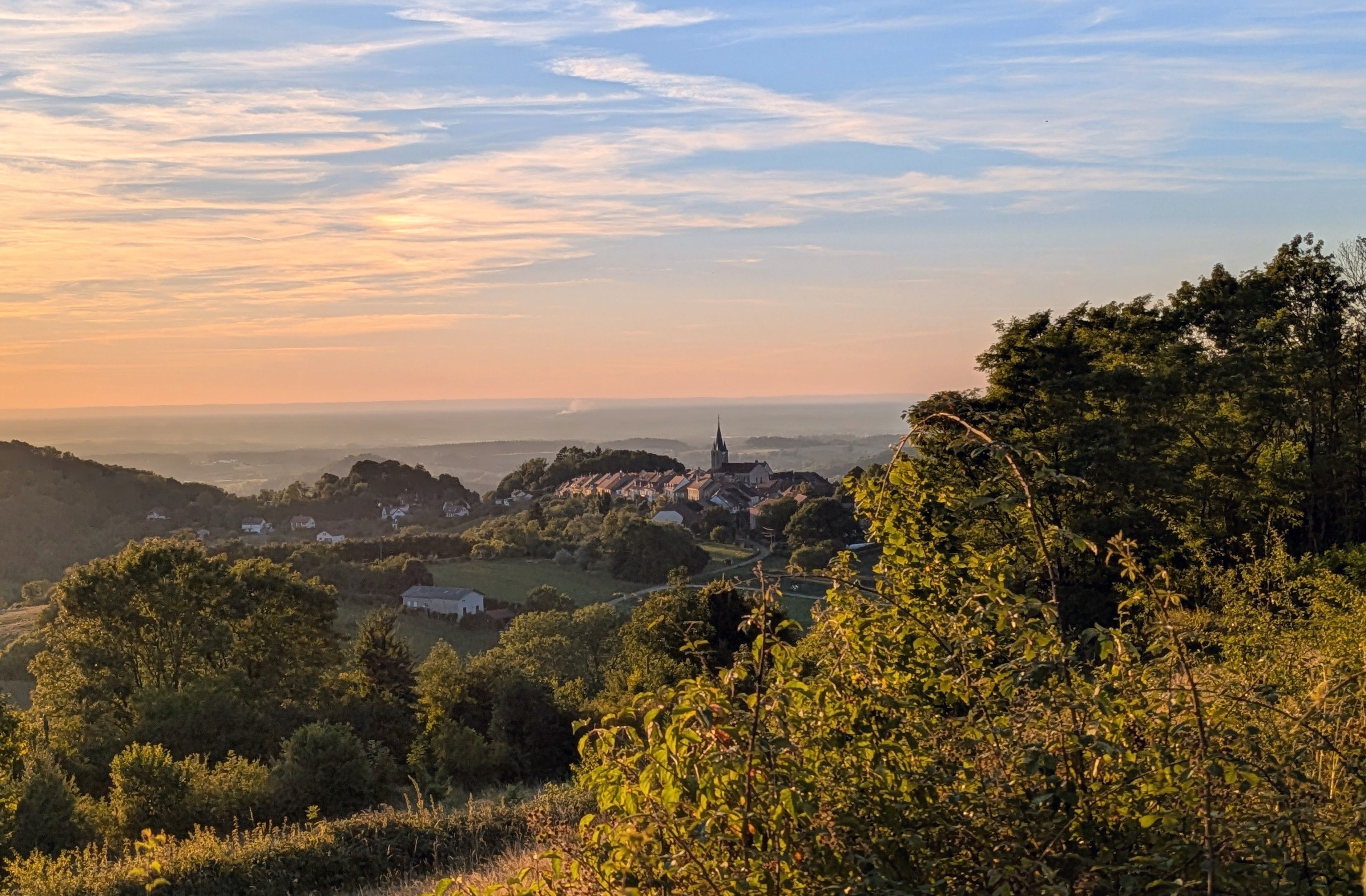 A town with a prominent church, surrounded by lush greenery and hills.