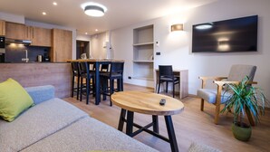 Un salon moderne comprenant un canapé, une table basse, un téléviseur et un coin repas avec des chaises et une table.