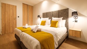 A modern hotel room with a large bed, wooden wardrobe, and a small bedside table. - Grand T3 familial en centre-ville (Lons-le-Saunier)