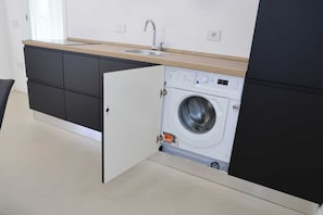 A compact kitchen with a built-in washing machine, a sink, and dark cabinetry. - The Campanile Near Pompeii, Naples,Amalfi Coast, Sorrento,vesuvius (Sant'Antonio Abate)
