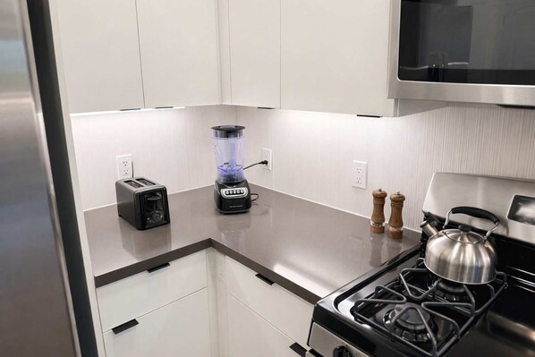 A kitchen with a toaster, blender, kettle, and salt and pepper shakers on the counter. - Artistic Getaway 10 Min to Disneyland With Pool GYM (Santa Ana)