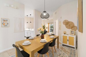 A dining area with a wooden table set for four, black chairs, and a hanging light fixture. - Updated Bahama Bay Condo | 2BR/2BA | Patio (Davenport)