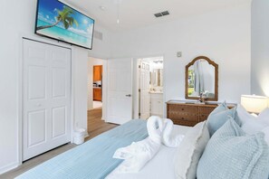 A hotel room with a bed, a dresser, a mirror, and a painting of a beach scene. - Nice ground floor upgraded condo in Bahama Bay (Davenport)