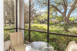 A balcony with a glass table and chairs, overlooking a well-maintained garden and a residential area. - Nice ground floor upgraded condo in Bahama Bay (Davenport)
