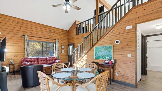 A wooden interior with a dining table, chairs, a red leather sofa, and a staircase. - The Travelers Nest For 8 (Branson)