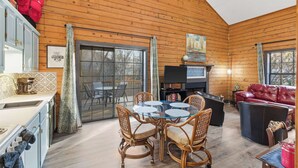 A cozy cabin interior with a dining area, a fireplace, and a television. - The Travelers Nest For 8 (Branson)