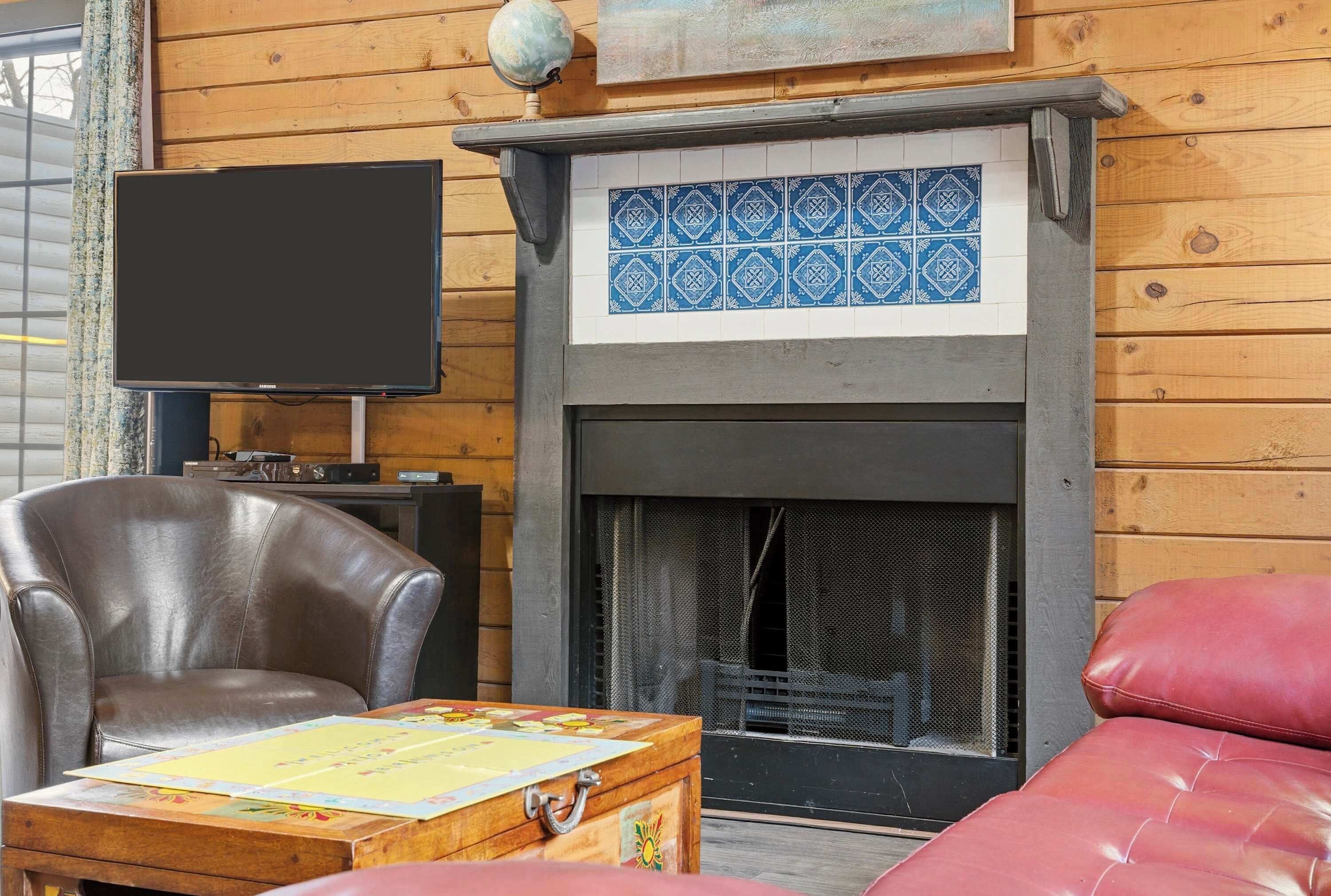 A cozy room with a fireplace, leather armchair, and a flat-screen TV.