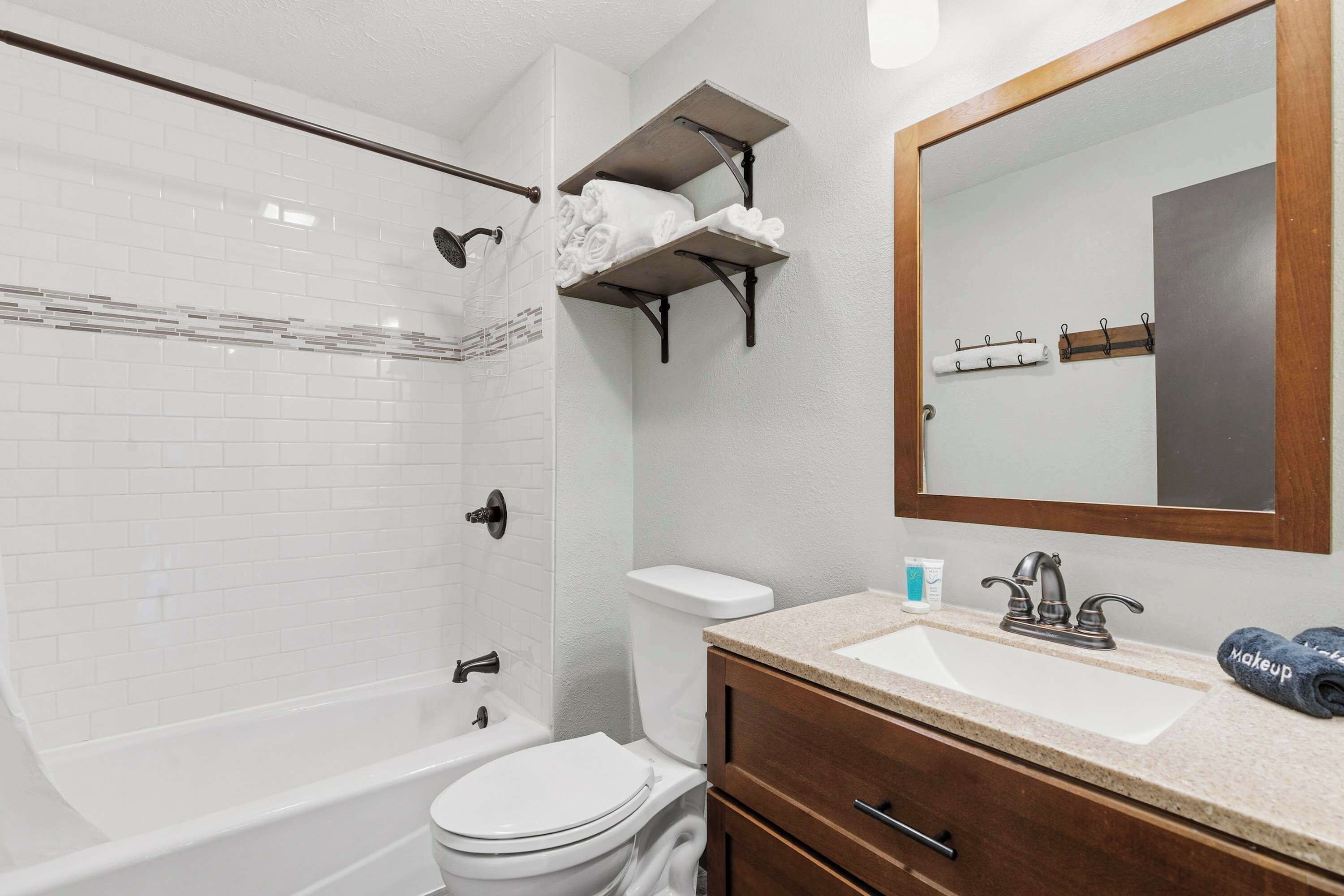 Une salle de bain avec une baignoire blanche, des toilettes, un lavabo avec un miroir et un porte-serviettes.