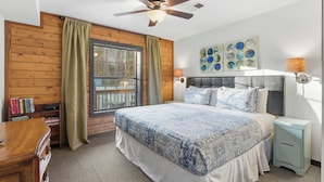 A bedroom with a bed, a nightstand, a ceiling fan, a window with curtains, and a bookshelf. - The Travelers Nest For 8 (Branson)