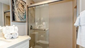 Un baño moderno con ducha de vidrio, inodoro y zona de lavamanos con toallas dobladas con cuidado.