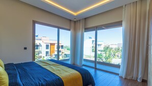 Una camera d'hotel moderna con un letto grande, vista sulla città e un balcone.