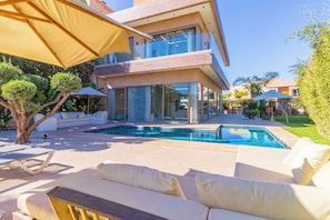 Uma casa moderna com piscina, móveis de exterior e um jardim bem cuidado.