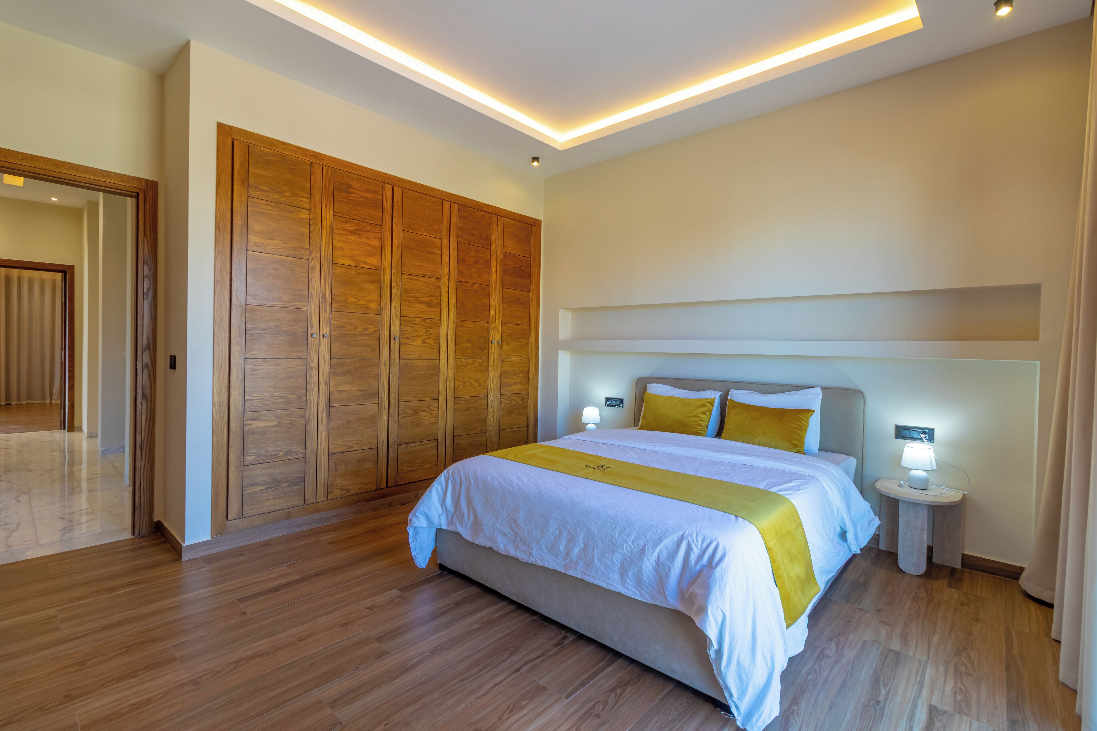 Une chambre d’hôtel moderne avec un grand lit, une armoire en bois et des lampes de chevet.