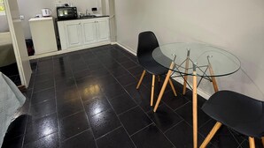 A compact living space with a kitchenette, a dining area with a glass table and black chairs, and a ceiling fan. - Hotel Casa Recoleta (Buenos Aires)