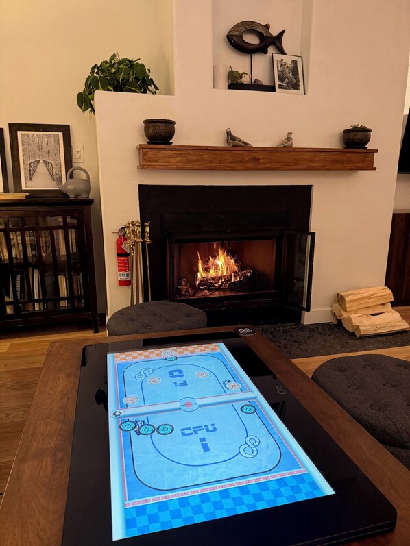A living room with a fireplace, a pool table, and a bookshelf.