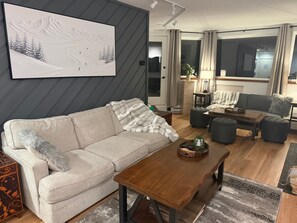 A modern living room with a sofa, coffee table, and a painting of a snowy landscape.