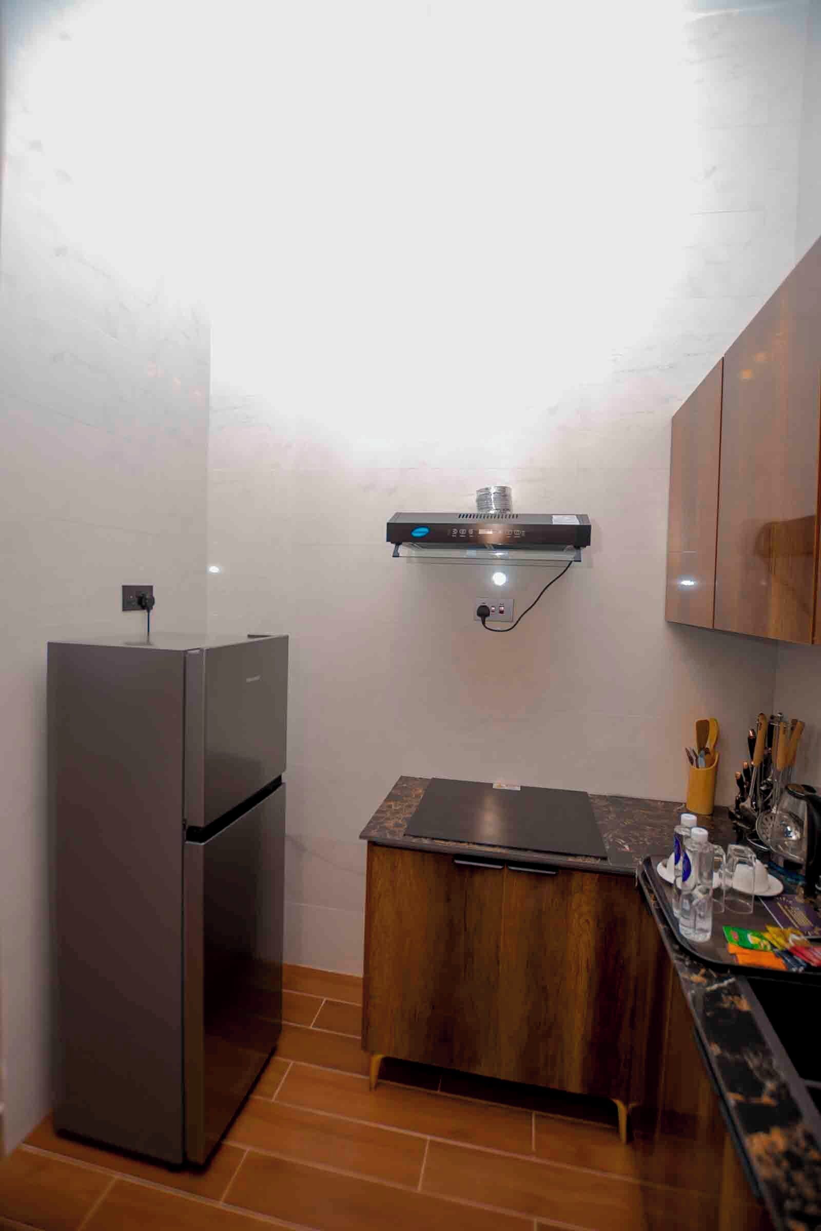 A compact kitchen with a built-in refrigerator, a wooden countertop, and a small sink.