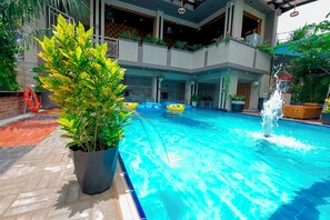 Ein beheiztes Hallenbad mit klarem Wasser, umgeben von Topfpflanzen und einer modernen Gebäudestruktur.