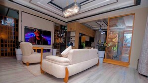 Un salon moderne avec un grand téléviseur à écran plat, un canapé beige et une table basse en bois.