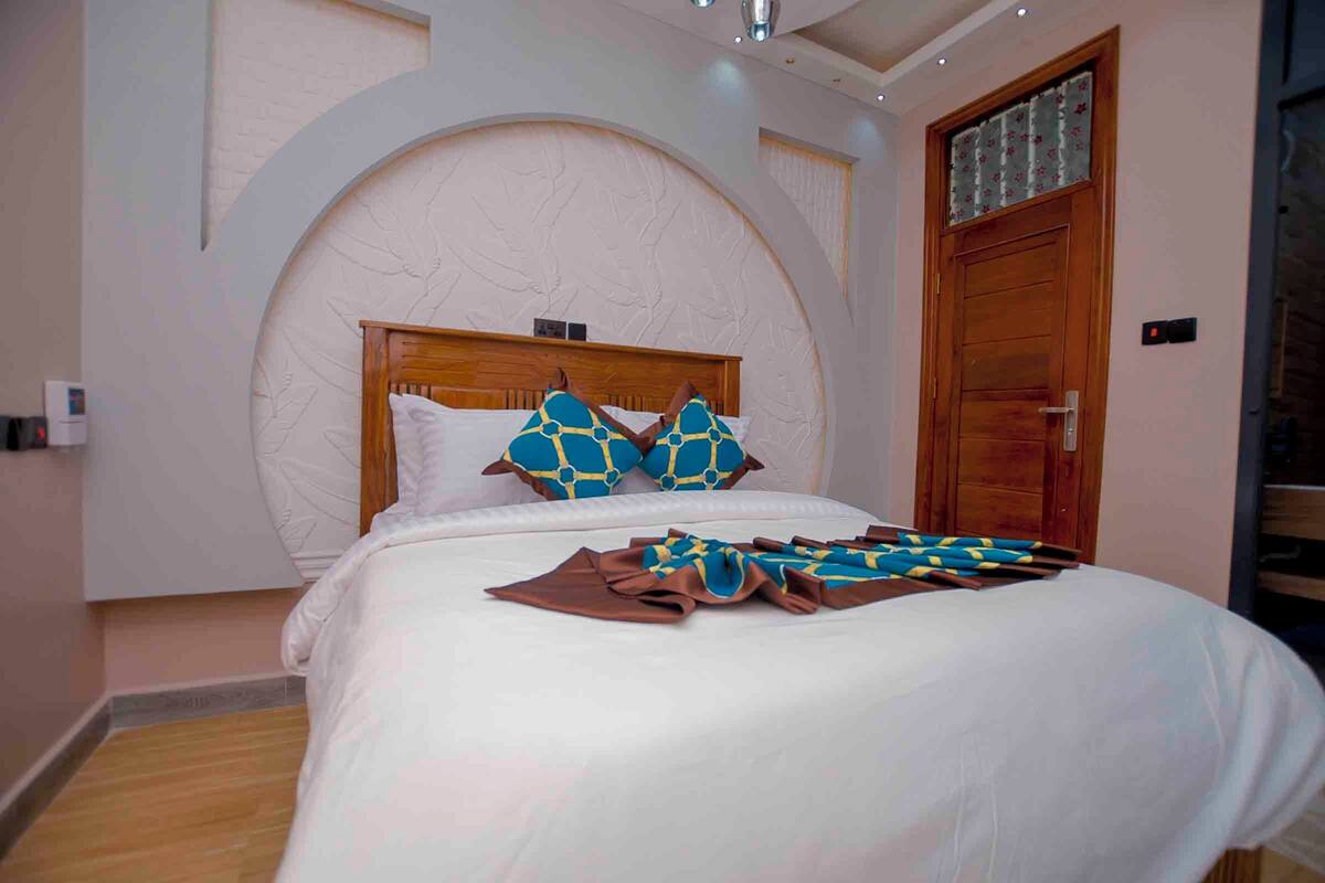 Una cama bien hecha con una colcha blanca y azul estampada, un cabecero de madera y dos almohadas a juego.