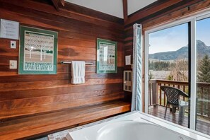 A wooden cabin bathroom with a large window and a view of the mountains. - Condo w/ Sweeping Mtn Views, Jetted Tub & 2 Balconies (Durango)