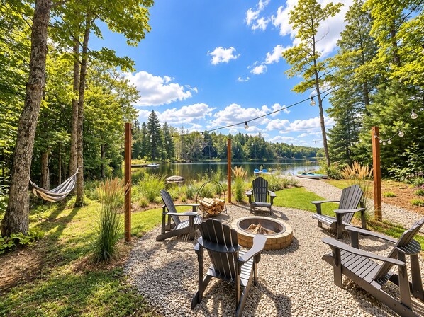 An outdoor seating area with Adirondack chairs, a fire pit, and a hammock.