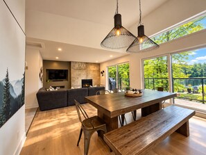 A modern interior with a wooden dining table, a sofa, and a fireplace. - Hôtel à la maison - Le Loma-sur-le-lac avec spa! (Chertsey)