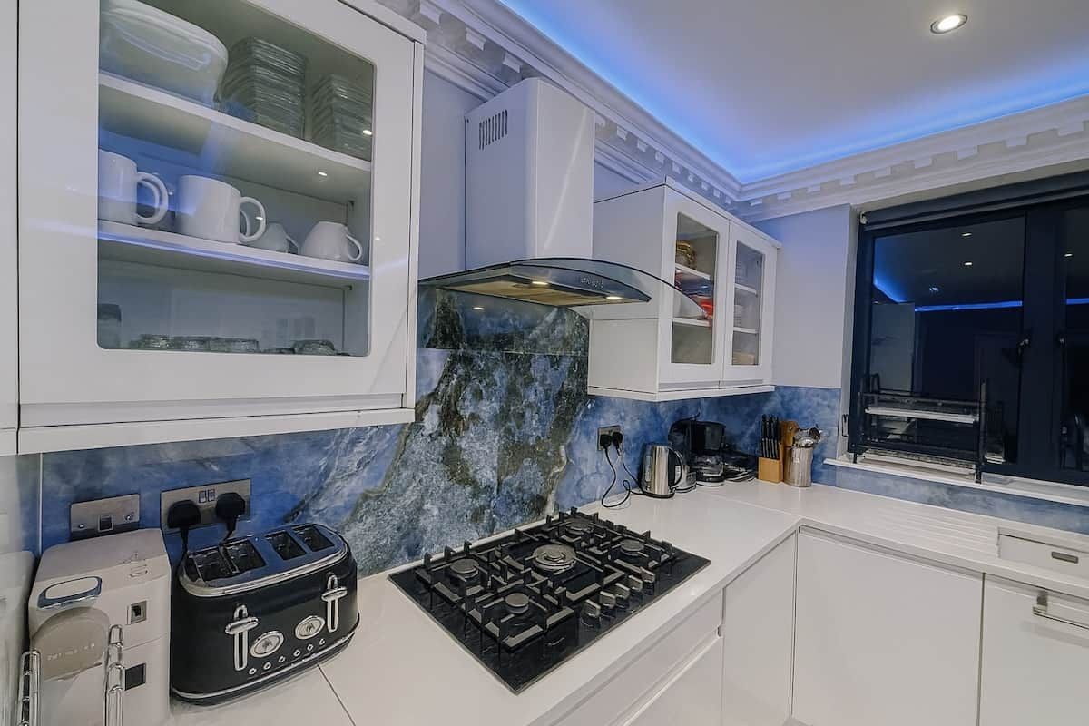 A modern kitchen with white cabinetry, a gas stove, and a marble backsplash.