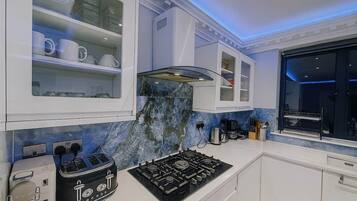 A modern kitchen with white cabinetry, a gas stove, and a marble backsplash.