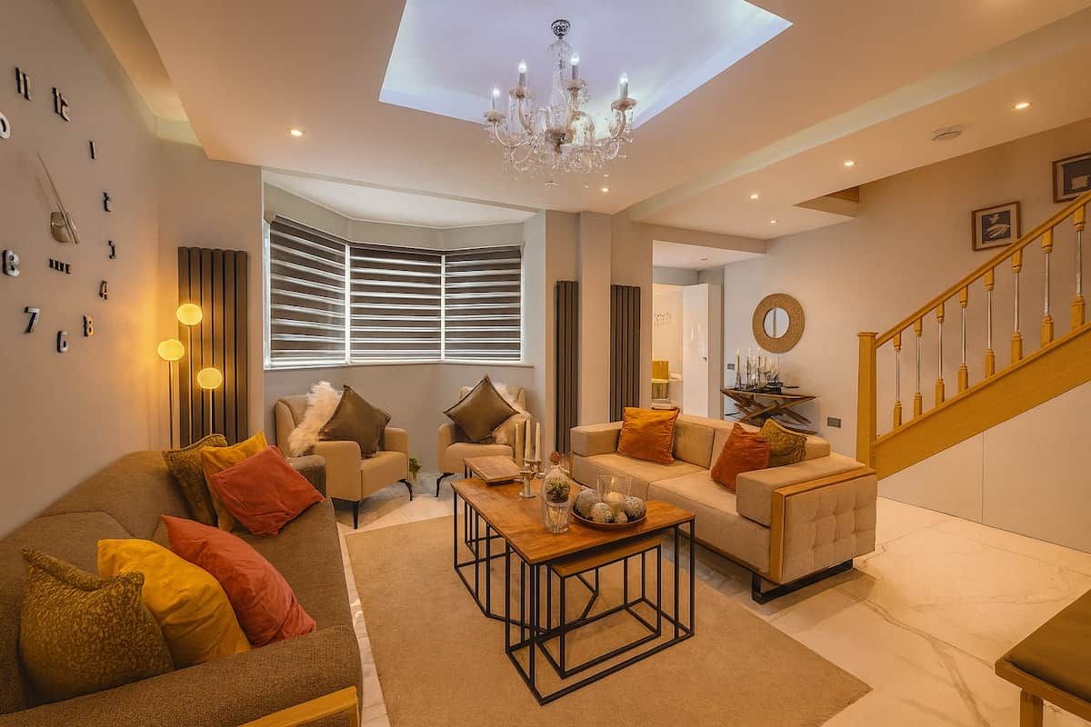 A modern living room with a sofa, armchairs, a coffee table, and a staircase.