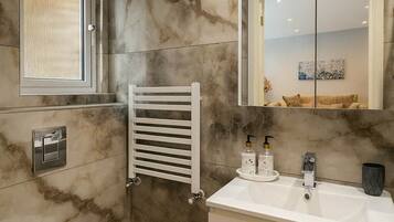 A bathroom with a white toilet, a white sink with a mirror above it, and a towel rack.