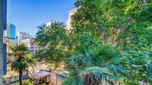 Un paysage urbain avec des bâtiments modernes, une rue animée par la circulation et de luxuriants arbres verdoyants.