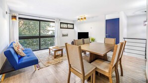 Un salon moderne avec un canapé bleu, une table à manger en bois et des chaises.