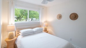 Ein Schlafzimmer mit einem Bett, zwei Nachttischlampen, einem Deckenventilator und zwei Wandhüten.