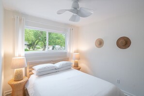 A bedroom with a bed, two bedside lamps, a ceiling fan, and two wall-mounted hats. - 2-bedroom house in Pet-Friendly E. Austin Home  - Close to downtown & Airport (Austin)