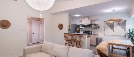 Een moderne woonkamer met een bank, een eettafel en een keuken op de achtergrond.