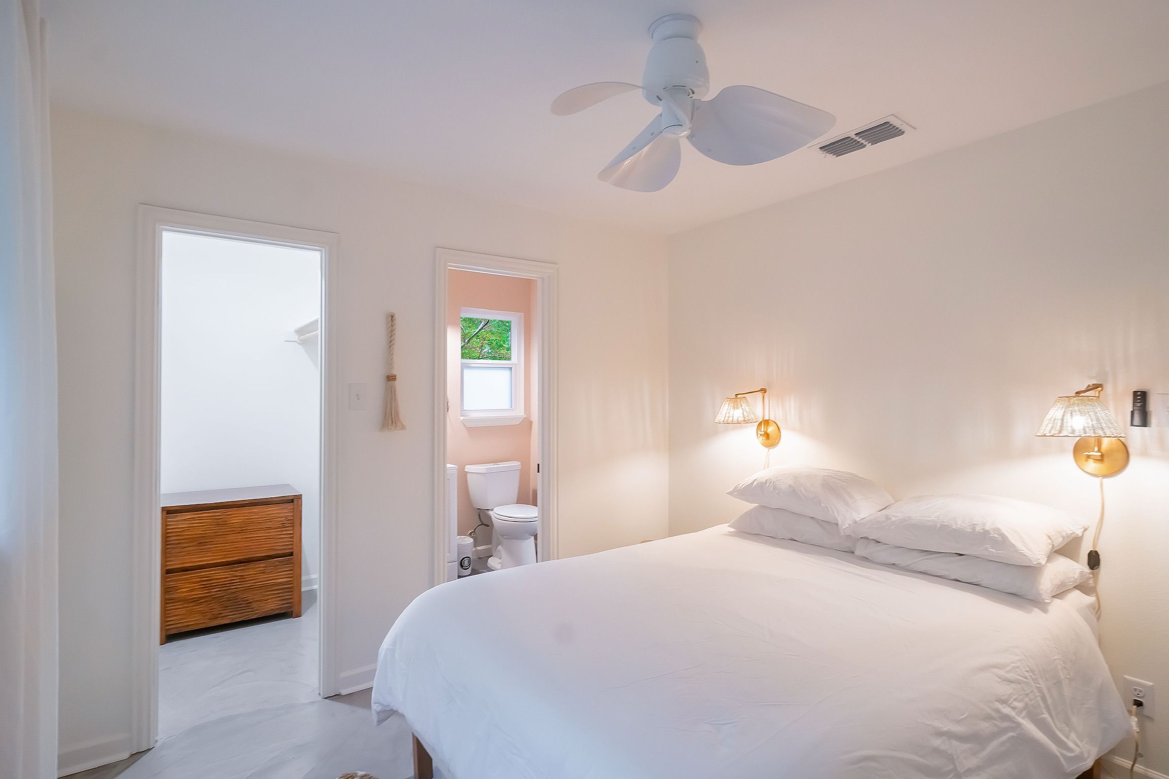 A bedroom with a bed, a ceiling fan, a window, and a door.