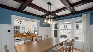 A dining room with a wooden table and chairs, a chandelier, and a view of the outside. - Spacious Craftsman Home | Family friendly | Arcade  | 5 Bedrooms (Portland)