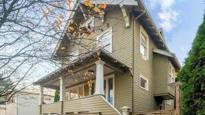A two-story house with a front porch, stone steps, and a small garden area. - Spacious Craftsman Home | Family friendly | Arcade  | 5 Bedrooms (Portland)