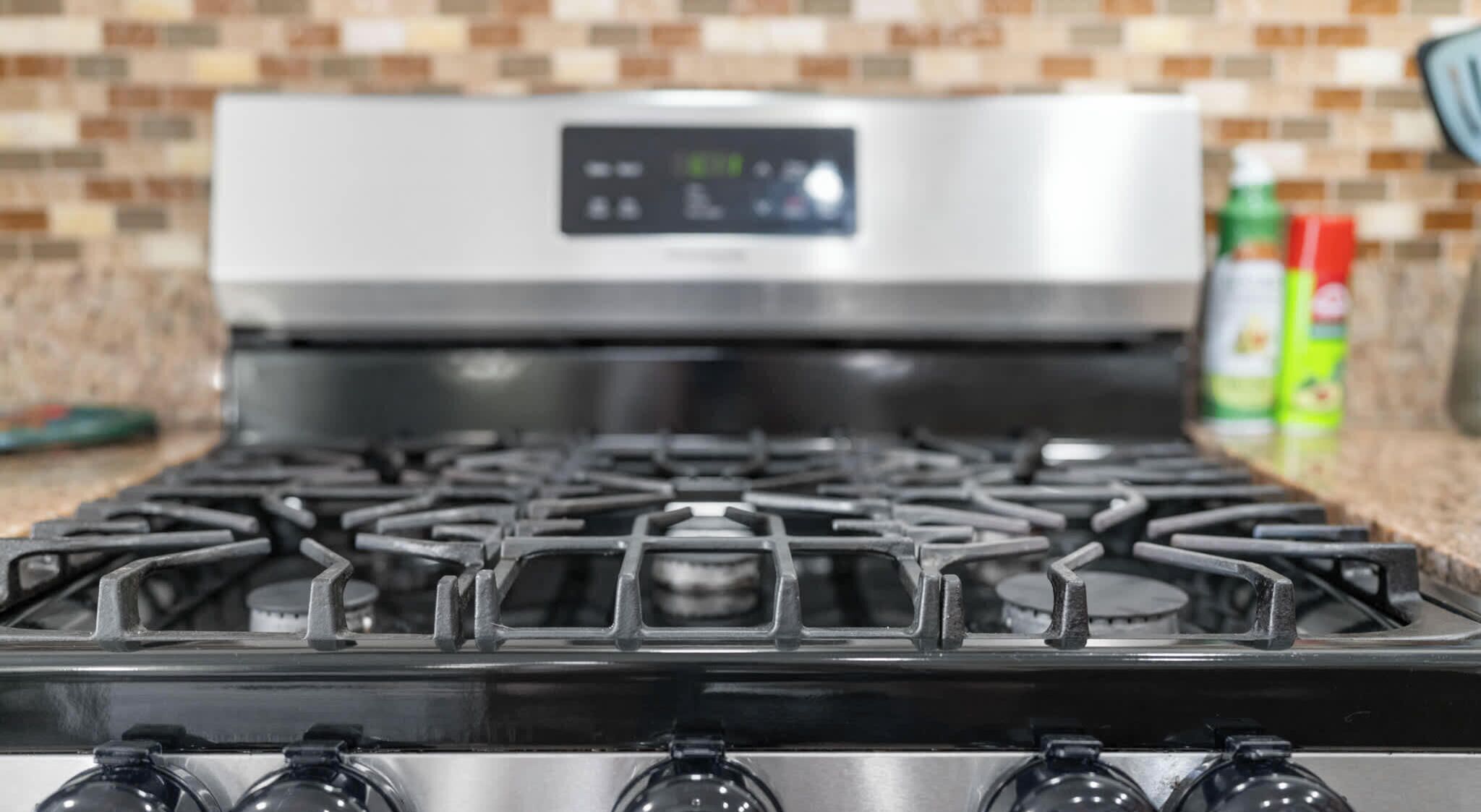 A kitchen with a gas stove, a digital control panel, and a tiled backsplash.