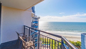 Een balkon met uitzicht op de oceaan en het strand.