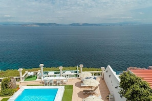 Area piscina con vista sul mare, arredi esterni e cielo sereno.