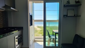 Una cocina moderna con un amplio ventanal y puerta corrediza de vidrio que da a un balcón con vista a la playa.